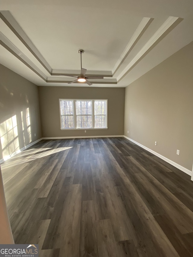 unfurnished room featuring dark hardwood / wood-style flooring, a tray ceiling, crown molding, and ceiling fan