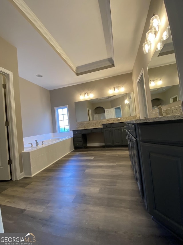 bathroom featuring crown molding, vanity, a raised ceiling, a relaxing tiled tub, and hardwood / wood-style floors