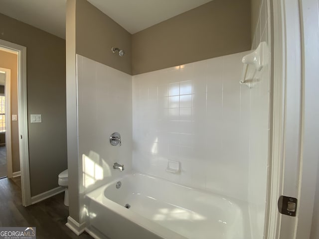 bathroom with tiled shower / bath, wood-type flooring, and toilet