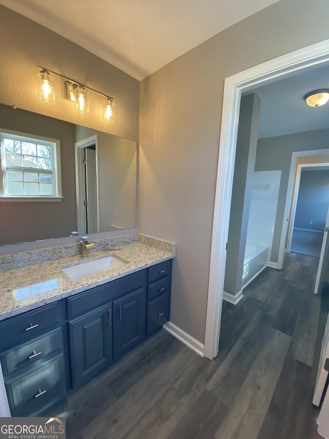 bathroom with a bath, vanity, and hardwood / wood-style floors