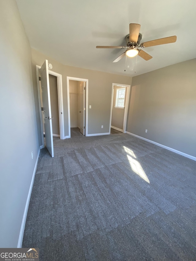 unfurnished bedroom with ceiling fan and dark carpet