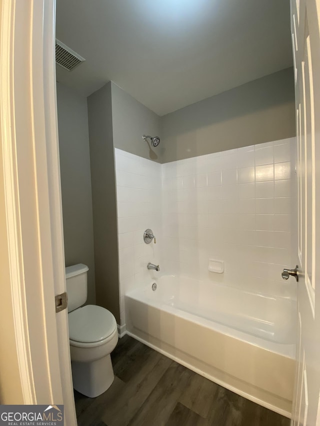 bathroom with shower / bath combination, wood-type flooring, and toilet