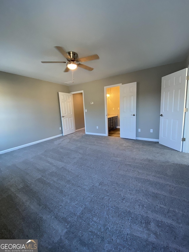 unfurnished bedroom featuring ensuite bath, ceiling fan, and dark colored carpet