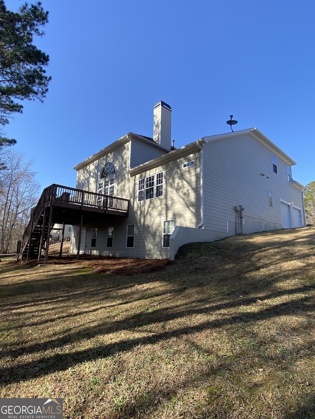 rear view of property featuring a wooden deck, a garage, and a lawn