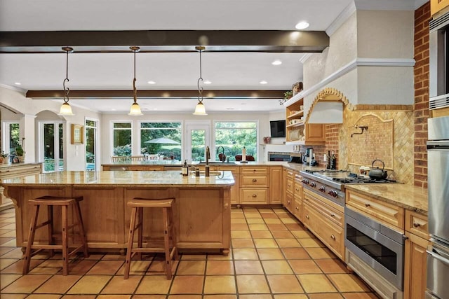 kitchen with pendant lighting, stainless steel appliances, light stone countertops, and a breakfast bar area