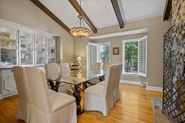 dining room featuring vaulted ceiling with beams and light wood-type flooring