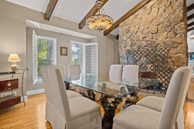 dining space with lofted ceiling with beams, a fireplace, and light hardwood / wood-style floors