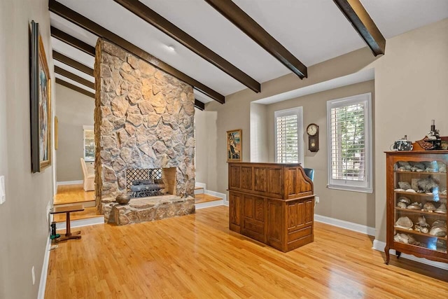 interior space with vaulted ceiling with beams, a fireplace, and light wood-type flooring