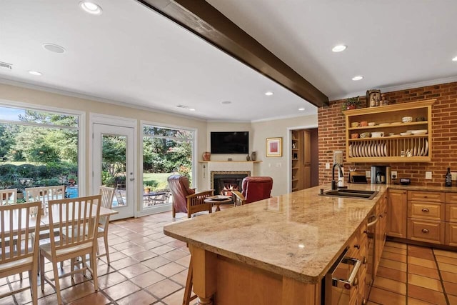 kitchen featuring sink, beam ceiling, a kitchen breakfast bar, light stone counters, and ornamental molding