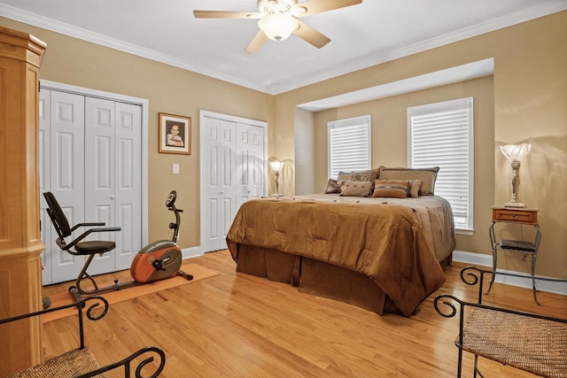 bedroom with multiple closets, ceiling fan, crown molding, and light hardwood / wood-style floors