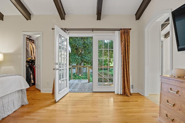 doorway featuring beam ceiling and light wood-type flooring