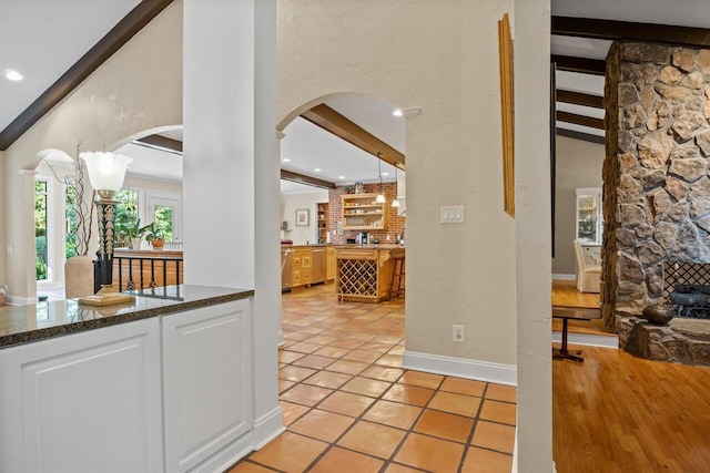 kitchen featuring pendant lighting, white cabinetry, dishwasher, light tile patterned floors, and beam ceiling