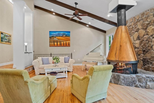 living room with high vaulted ceiling, beam ceiling, light hardwood / wood-style floors, and a wood stove