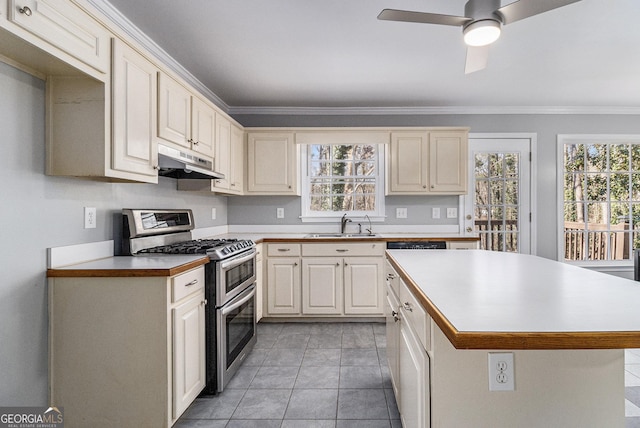 kitchen featuring sink, crown molding, ceiling fan, double oven range, and cream cabinetry