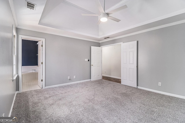 unfurnished bedroom featuring crown molding, ceiling fan, ensuite bathroom, carpet flooring, and a tray ceiling