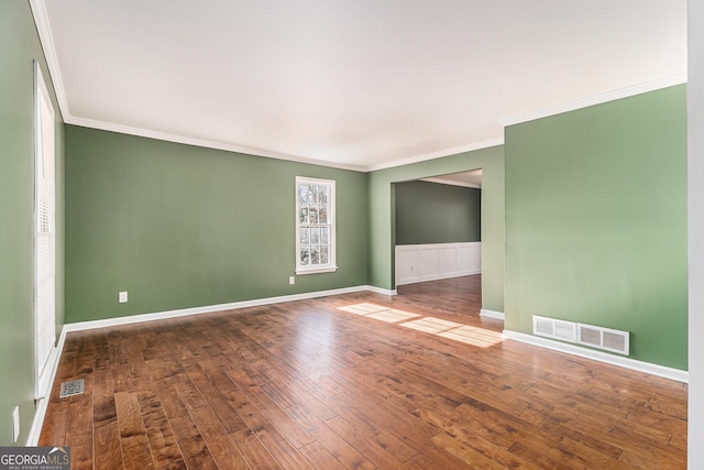 empty room featuring wood-type flooring and ornamental molding