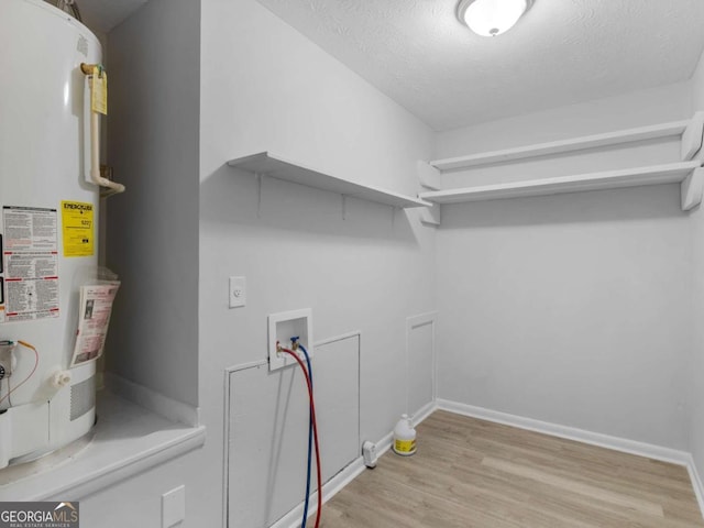 interior space featuring washer hookup, water heater, a textured ceiling, and light wood-type flooring