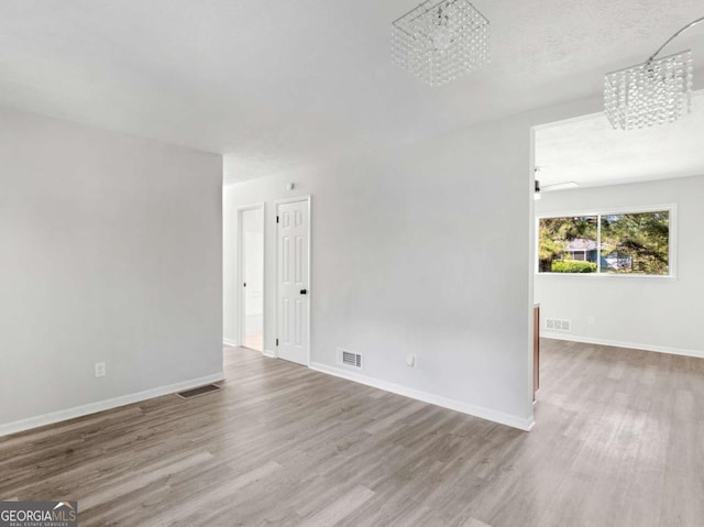 empty room featuring a notable chandelier, hardwood / wood-style flooring, and a textured ceiling