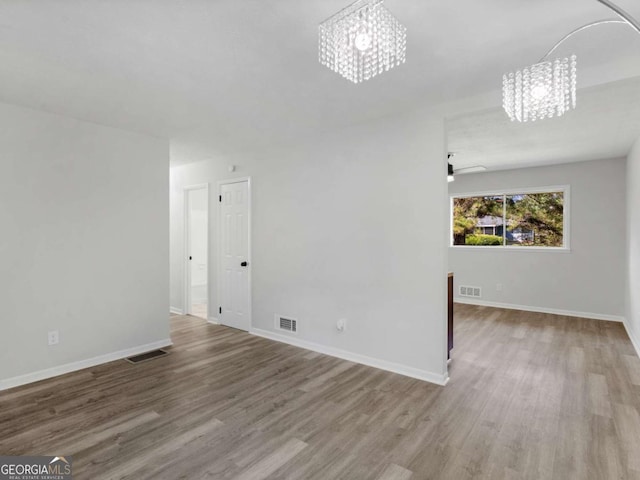 unfurnished living room with hardwood / wood-style floors and an inviting chandelier