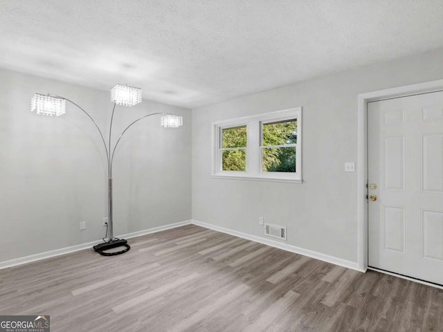 interior space featuring a chandelier, a textured ceiling, and light wood-type flooring