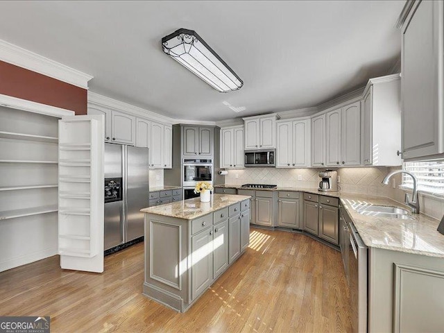 kitchen featuring stainless steel appliances, sink, a kitchen island, and light wood-type flooring