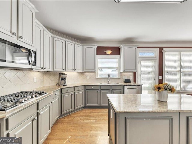 kitchen with sink, gray cabinetry, tasteful backsplash, light wood-type flooring, and appliances with stainless steel finishes