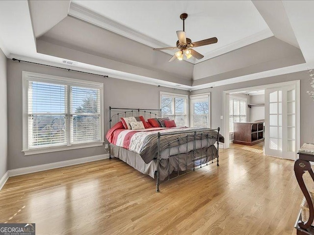 bedroom featuring a tray ceiling, ornamental molding, ceiling fan, and light wood-type flooring