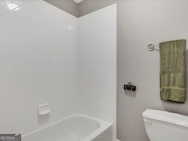 bathroom with tiled shower / bath combo and toilet