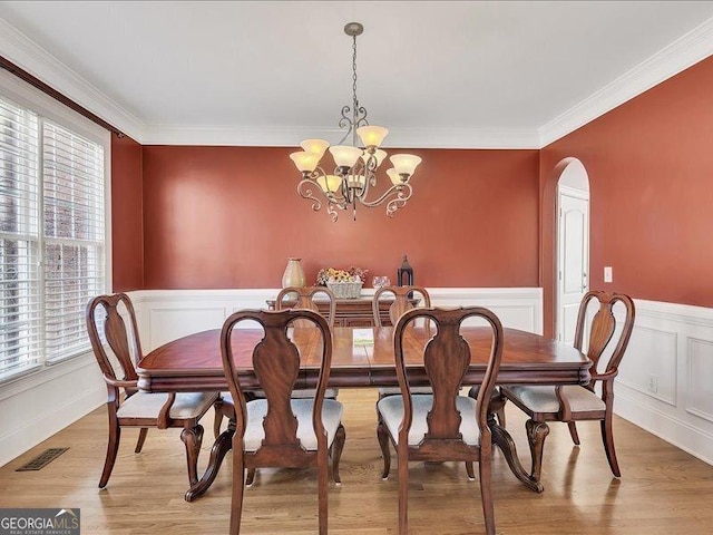 dining room featuring an inviting chandelier, ornamental molding, and light wood-type flooring