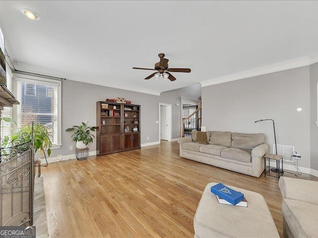 living room with ceiling fan, ornamental molding, and light wood-type flooring