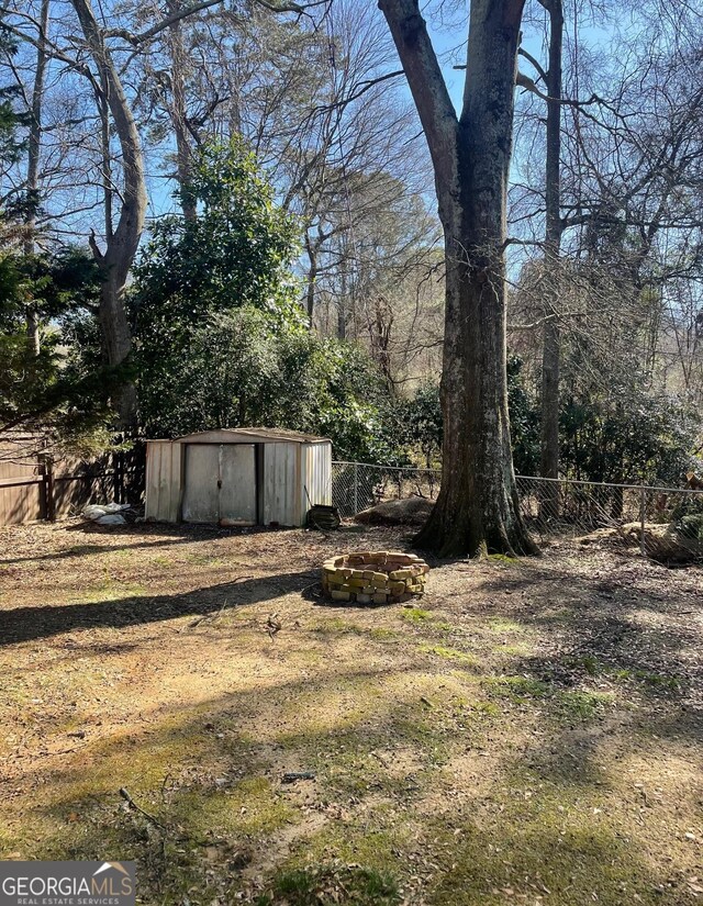 view of yard with a storage shed and an outdoor fire pit