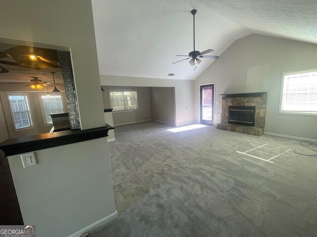 unfurnished living room with ceiling fan, a fireplace, a healthy amount of sunlight, and carpet flooring