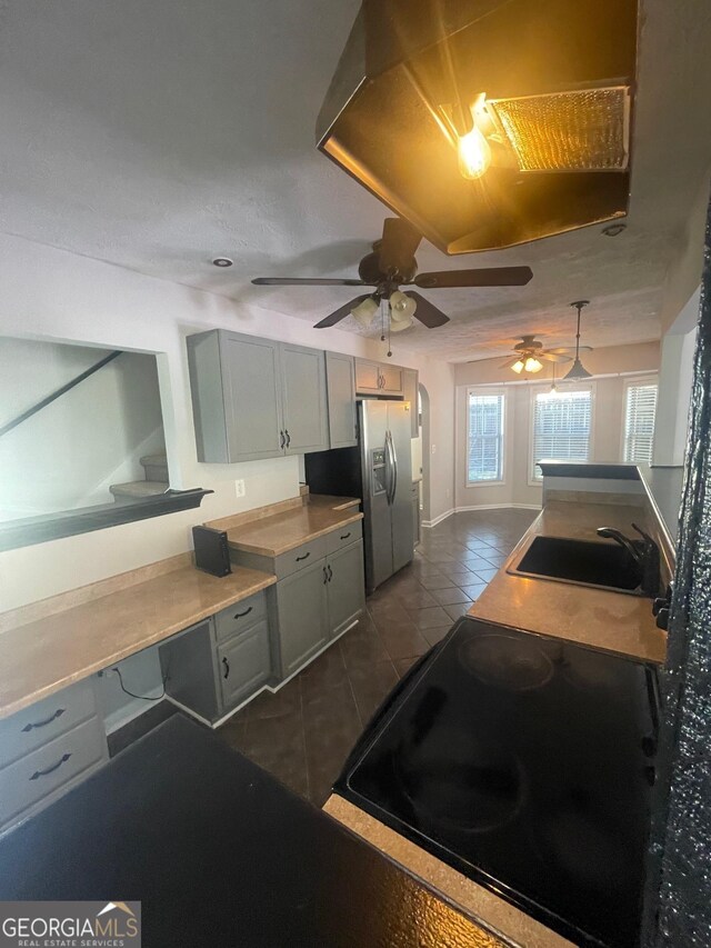 kitchen with dark tile patterned floors, decorative light fixtures, sink, and gray cabinetry