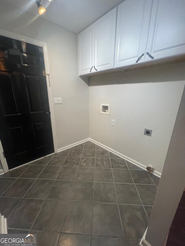 laundry area featuring hookup for a washing machine, dark tile patterned floors, hookup for an electric dryer, and cabinets