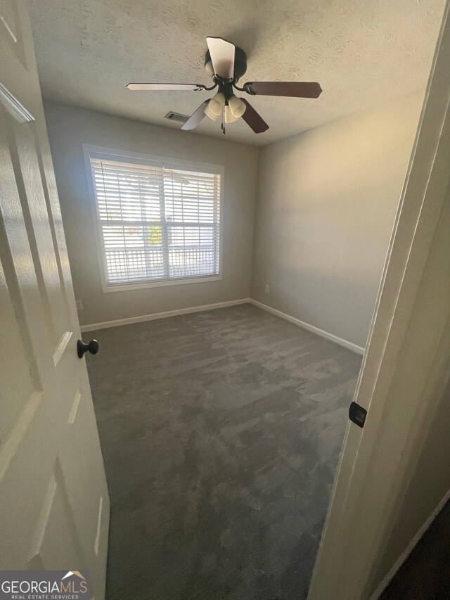 carpeted spare room with ceiling fan and a textured ceiling