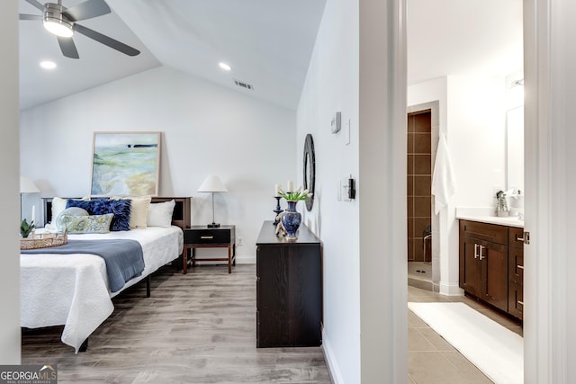 bedroom with baseboards, visible vents, connected bathroom, vaulted ceiling, and light wood-type flooring