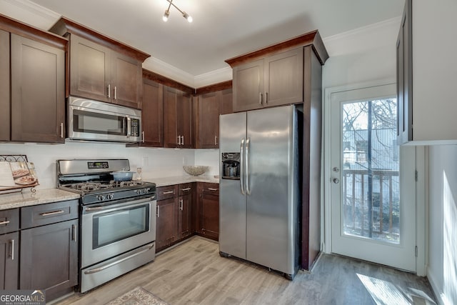 kitchen with light stone counters, crown molding, dark brown cabinets, and stainless steel appliances