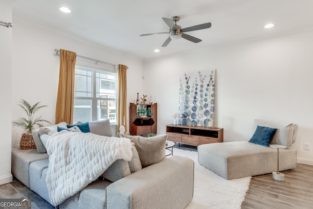 living room featuring hardwood / wood-style flooring, crown molding, and ceiling fan