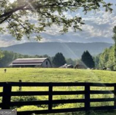 view of gate with a rural view, a mountain view, and a lawn