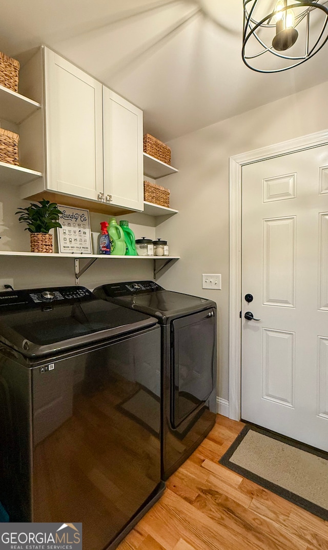 laundry room featuring cabinets, washer and dryer, and light hardwood / wood-style flooring