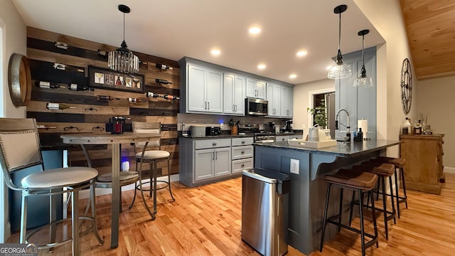 kitchen featuring pendant lighting, stainless steel appliances, a kitchen breakfast bar, and light wood-type flooring