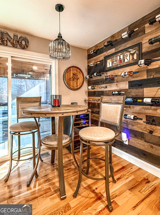 dining area with a chandelier, hardwood / wood-style floors, and wooden walls