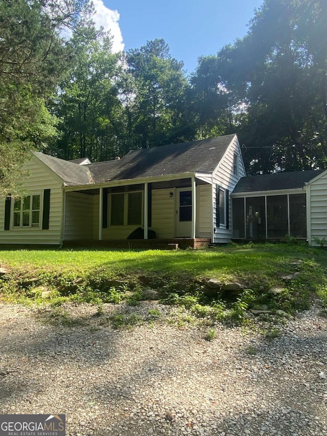 view of front of home with a sunroom and a front lawn