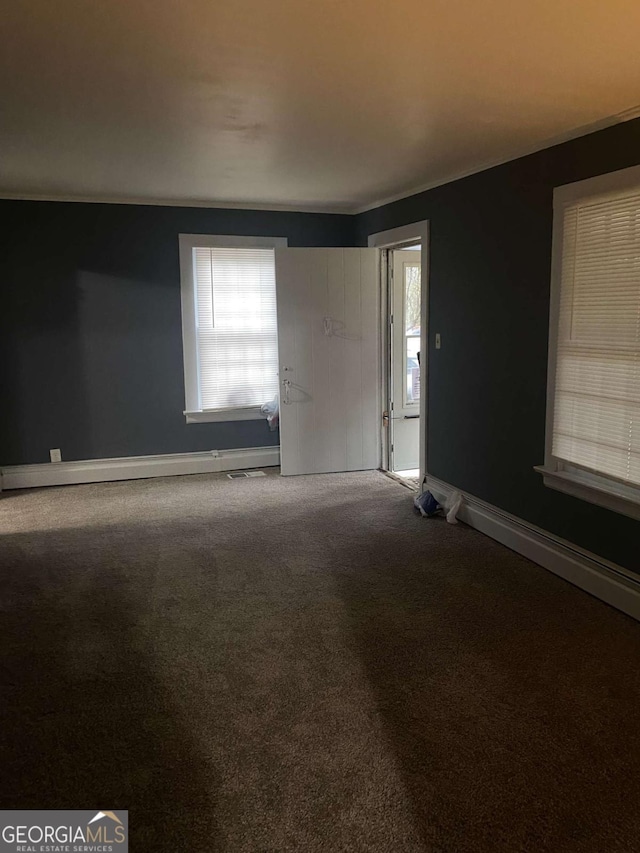 carpeted spare room featuring plenty of natural light and baseboard heating