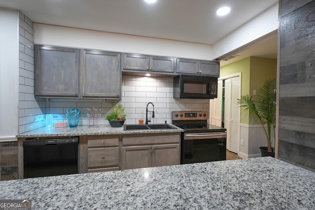 kitchen with sink, backsplash, black appliances, and light stone countertops