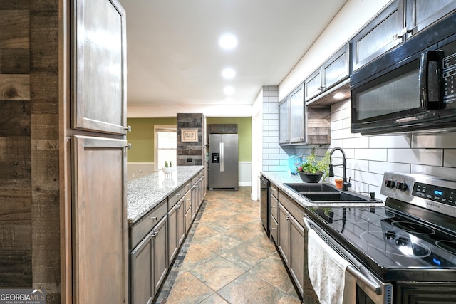 kitchen with sink, dark brown cabinets, light stone counters, black appliances, and decorative backsplash