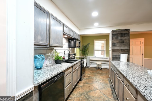 kitchen featuring tasteful backsplash, light stone countertops, sink, and black appliances