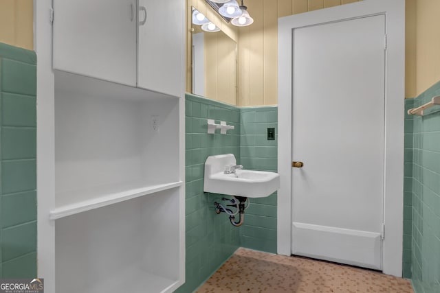 bathroom featuring sink and tile walls