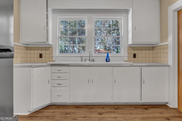 kitchen featuring white cabinetry, sink, tasteful backsplash, and light wood-type flooring