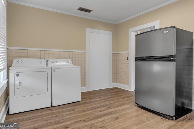 washroom with crown molding, tile walls, independent washer and dryer, and light hardwood / wood-style floors